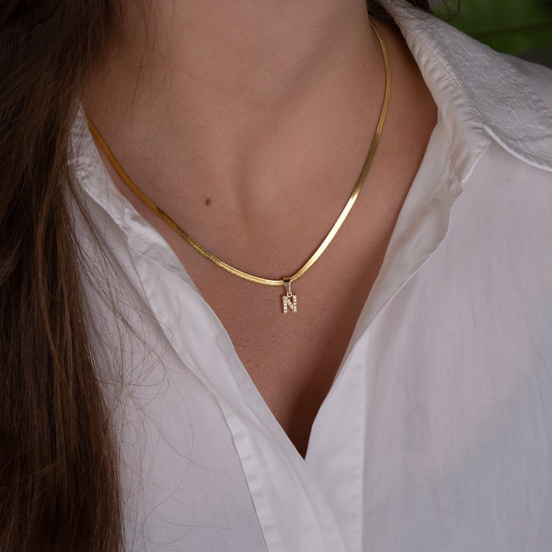 The perfect minimalist personalized necklace with the initial letter you want :-) Delicate herringbone chain necklace 2mm with an initial charm of your choise. The chain is made from gold plated stainless steel and the charm ( around 8mm)