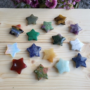 Könnte beinhalten: Eine Sammlung von 14 sternförmigen, polierten Steinen in verschiedenen Farben, darunter Grün, Blau, Rot, Gelb, Weiß und Braun. Die Steine sind auf einer Holzoberfläche angeordnet.