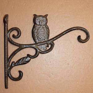 May include: A decorative cast iron wall hook featuring an owl perched on a branch. The hook has a dark, textured finish and includes decorative leaf and scroll details. Perfect for hanging plants or lanterns.