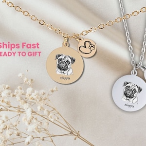 May include: Two silver necklaces with a round pendant featuring a black and white image of a pug dog. Each pendant has the word "Happy" inscribed below the image. One necklace has a small heart charm with a paw print on it.