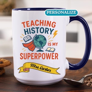 May include: White ceramic coffee mug with a blue rim and handle. The mug features a graphic of a globe with a red cape, books, and lightning bolt. The text reads "Teaching History is my Superpower" with a yellow banner below that says "Mrs. Carter".
