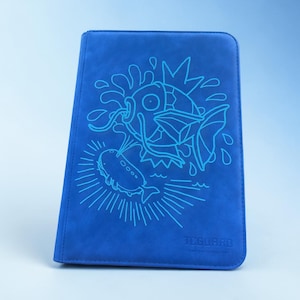 May include: Blue card binder with a detailed illustration of a fish with a crown and another fish. The design is in a lighter shade of blue. The text "TCGARD" is at the bottom right corner.