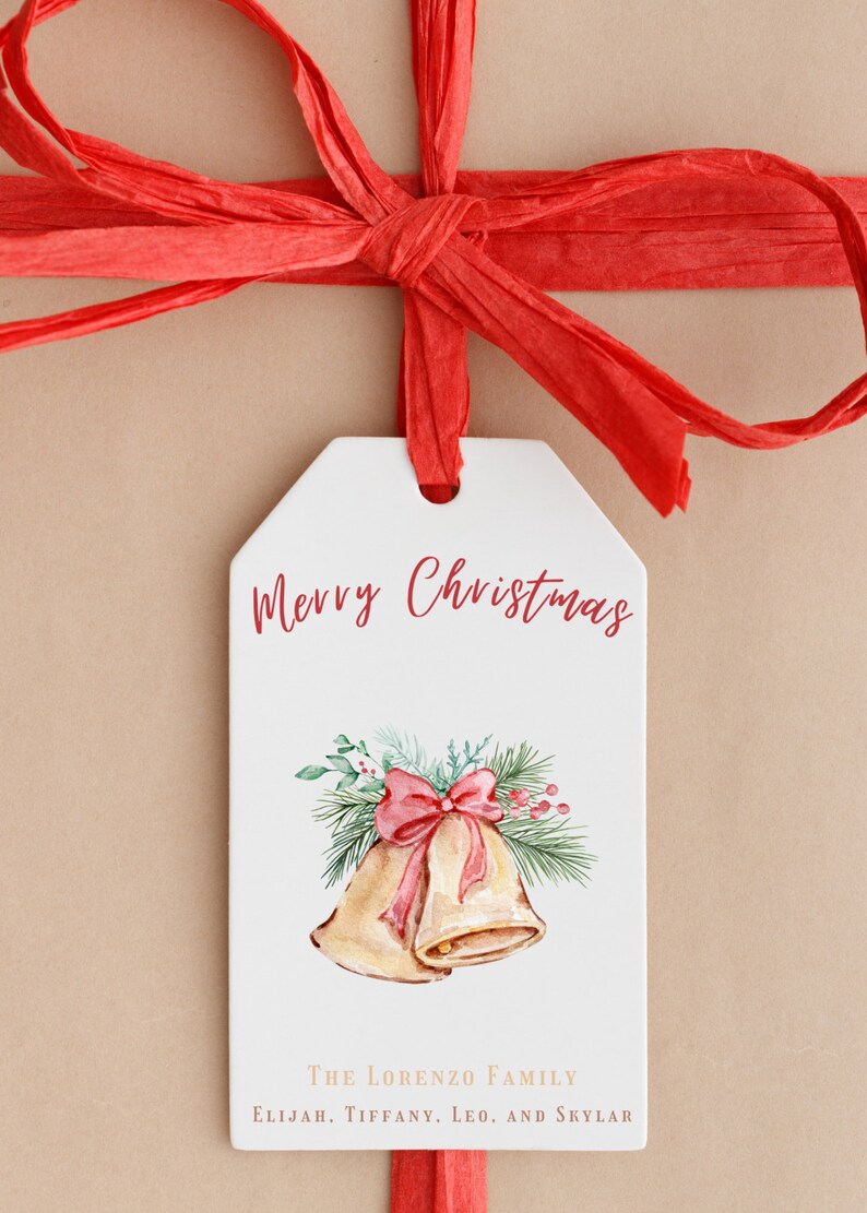 May include: A white gift tag with the text "Merry Christmas" in red cursive. The tag features a watercolor illustration of two gold bells with a red bow and green pine branches. The text "The Lorenzo Family" and "Elijah, Tiffany, Leo, and Skylar" is printed in brown at the bottom of the tag.