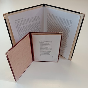 May include: A black leather-bound folder with three pages. The front page has the title "Predigt über Titus 3,4-7" printed in black. The second page has the text "Führbitten" printed in black. The third page has text printed in black.