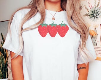 May include: White t-shirt with a graphic of three red strawberries with green leaves.