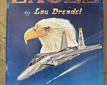 May include: A vintage book cover titled "EAGLE" by Lou Drendel. The cover features a detailed illustration of an eagle's head and a modern military aircraft. The background is a gradient of blue. The text "squadron/signal publications" is at the bottom.