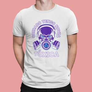 May include: White t-shirt with a purple skull wearing a gas mask and the text "Cuidado Tengo Novia Tóxica" in purple.