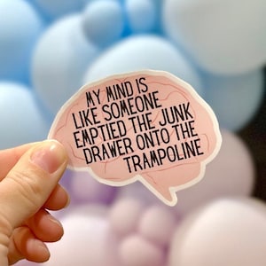 May include: A pink brain-shaped sticker with the text "My mind is like someone emptied the junk drawer onto the trampoline."