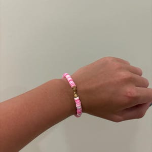 May include: A pink and white beaded bracelet with a gold clasp.