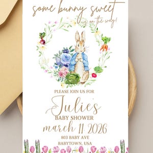 Pode incluir: Convite para chá de bebé com uma ilustração em aquarela de um coelhinho com um casaco azul, rodeado por uma coroa de flores. O convite inclui o texto "some bunny sweet is on the way!" e os detalhes do chá de bebé da Julie.