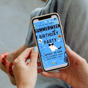 K&ouml;nnte beinhalten: Ein Smartphone zeigt eine blaue Einladung f&uuml;r eine "Summerween Birthday Party". Das Design umfasst einen Geist mit Sonnenbrille, Flederm&auml;use, ein Spinnennetz und einen Totenkopf. Der Text lautet "August 30 6PM 123 Flower Lane Anytown, USA."