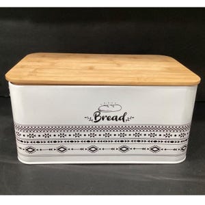 Slightly angled front view of the white bread box with a wooden lid and tribal border graphics.