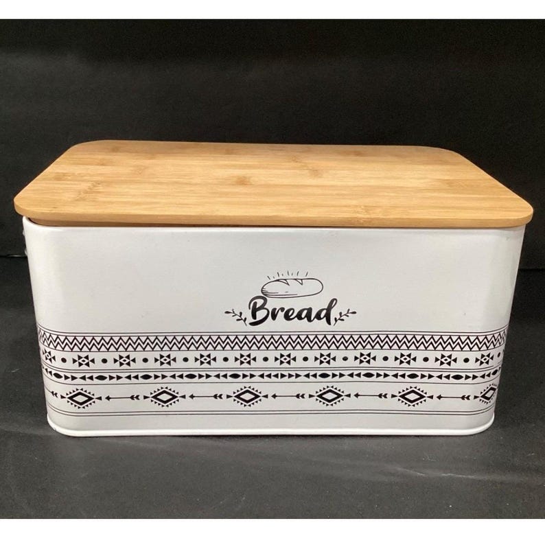 Slightly angled front view of the white bread box with a wooden lid and tribal border graphics.