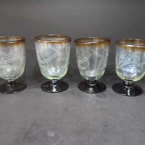 Puede incluir: Juego de cuatro vasos transparentes de vidrio con un diseño esmerilado y un borde marrón. Los vasos tienen un tallo corto y una base redonda.