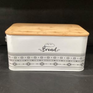 Front-facing product shot of the white metal bread box with its wooden lid.