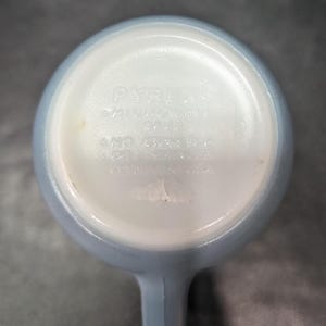 Underside of a light blue mug showing molded text that reads Pyrex Microwave Safe.