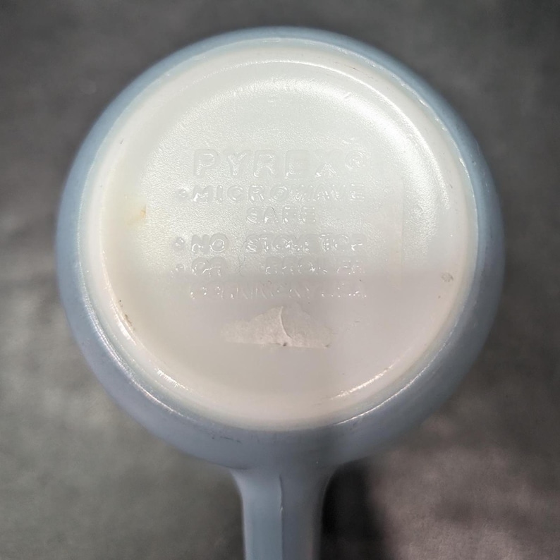 Underside of a light blue mug showing molded text that reads Pyrex Microwave Safe.