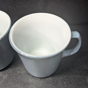 Angle shot of a light blue coffee mug facing forward with its handle on the right side against a dark gray background.