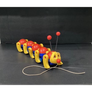 May include: A pull-along toy caterpillar featuring a segmented body with red spherical sections and blue connectors. It has yellow legs, a yellow head with a red nose, and two antennae with red tips attached to springs. A white string is attached.
