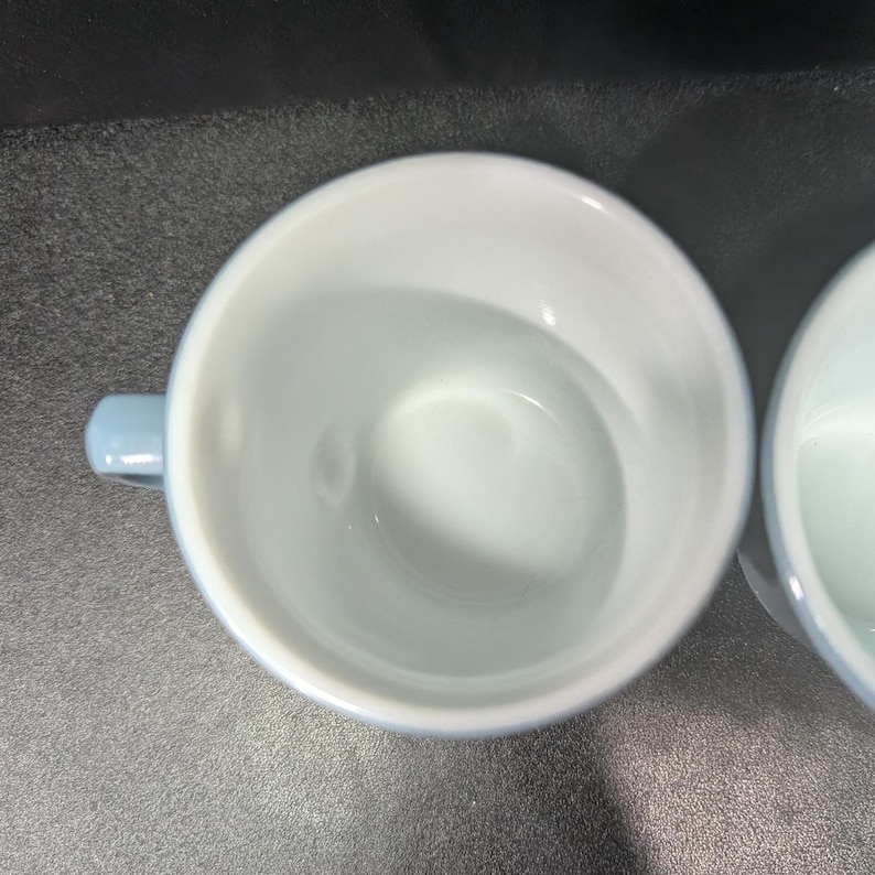 Top-down angled view looking inside a light blue ceramic coffee mug with a white interior.