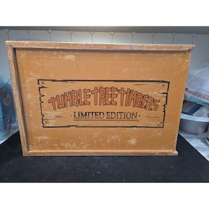 May include: A wooden box with the text "Tumble Tree Timbers - Limited Edition" in orange and black. The box is a light brown color and appears to be made of wood. The text is in a rustic font.