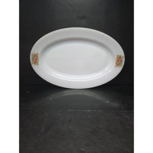 May include: White oval serving platter with floral accents. The plate has a smooth, glossy finish and features small clusters of pink, yellow, and green flowers on each end. A classic piece for serving appetizers or desserts.