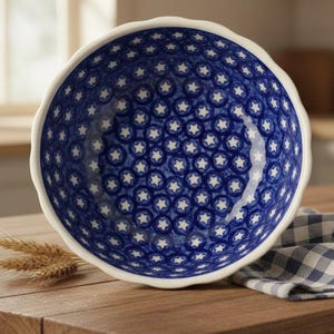 May include: A round ceramic bowl with a scalloped edge, featuring a deep blue interior and exterior decorated with a repeating pattern of white stars enclosed in blue circles. The bowl has a white rim and a smooth, glossy finish throughout.