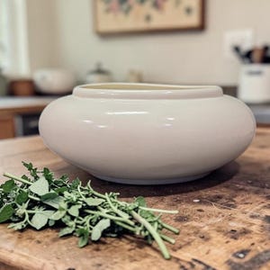 May include: A set of three ceramic mugs with a speckled, matte finish. The mugs are in shades of cream, light gray, and dark gray. Each mug has a simple, minimalist design, perfect for coffee or tea.
