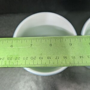 Top-down view of the inside of a light blue coffee mug with a green ruler measuring across the circular rim.