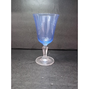 May include: A vintage blue glass goblet with a clear stem and base. The goblet has a flared rim and a delicate, elegant design. The glass is a light, translucent blue color.