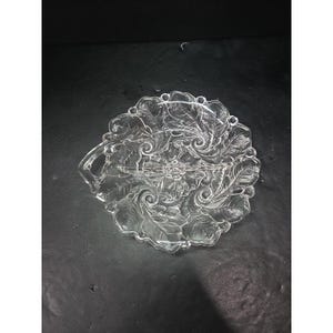 May include: Clear glass serving dish with a handle and a floral and leaf design. The dish is divided into three sections and has a scalloped edge. The design is etched into the glass.