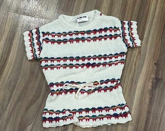 Könnte beinhalten: Weißes, ärmelloses Strickkleid mit einem rot-blau-grünen Streifenmuster. Das Kleid hat eine Kordelzugtaille und ein 'a-teen' Etikett.