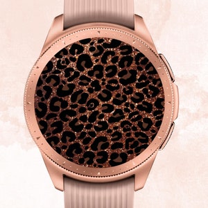 Könnte beinhalten: Eine roségoldene Smartwatch mit einem Zifferblatt mit Leopardenmuster. Das Armband der Uhr ist aus hellrosa Silikon.