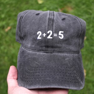 May include: A black baseball cap with white embroidery that reads "2+2=5".