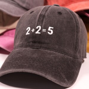 May include: A black denim baseball cap with white embroidery that reads "2+2=5".
