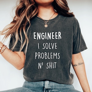 Pode incluir: Uma camiseta cinza escura com o texto "ENGINEER I SOLVE PROBLEMS N' SHIT" em letras brancas.