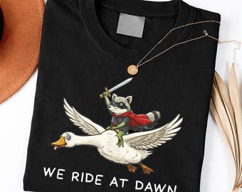 We Ride at Dawn Funny Raccoon Riding Goose Chaotic Animal shirt