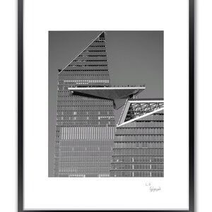 A framed black and white photo shows a modern building with a triangular roof and a large, flat observation deck.