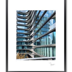 A framed color photo shows a modern building with wavy, horizontal lines and many windows reflecting the sky.