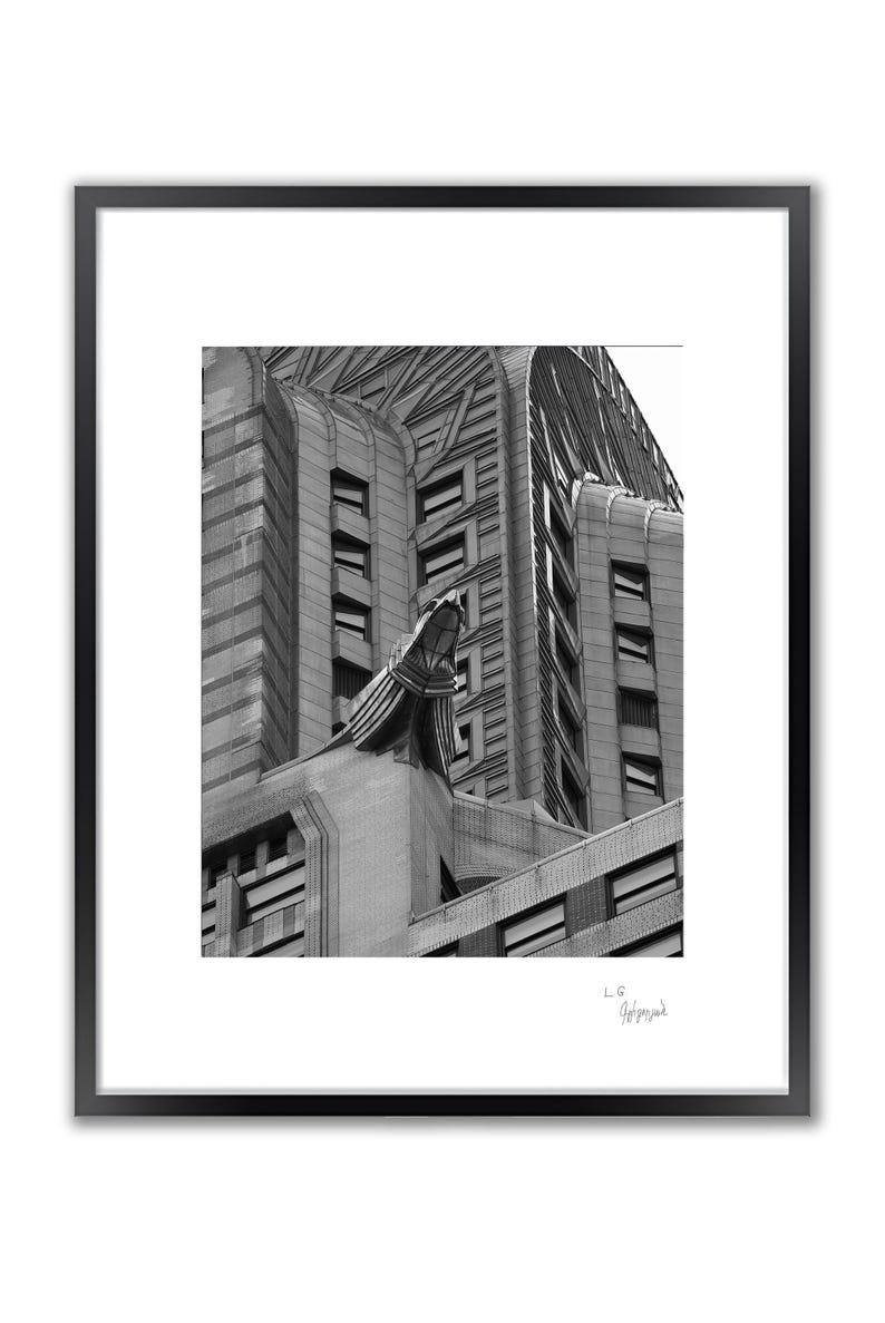 A framed black and white photo shows a close-up of the upper section of a building with a large gargoyle sculpture.