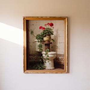 K&ouml;nnte beinhalten: Gerahmtes Gem&auml;lde einer Vintage-Toilette mit einer Topfpflanze. Die Pflanze hat rote Bl&uuml;ten und gr&uuml;ne Bl&auml;tter. Das Gem&auml;lde hat einen goldenen Rahmen und ist an einer wei&szlig;en Wand befestigt.