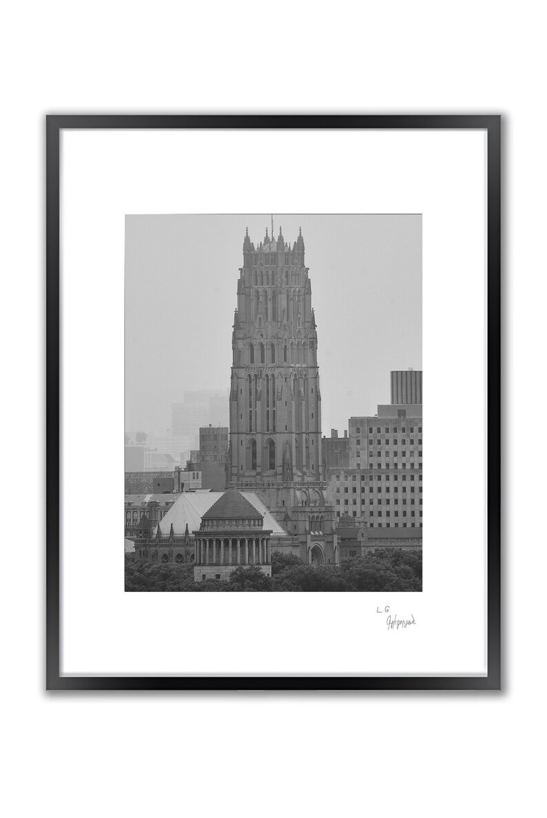A framed black and white photo shows a tall, gothic-style building with a pointed roof, surrounded by other buildings.