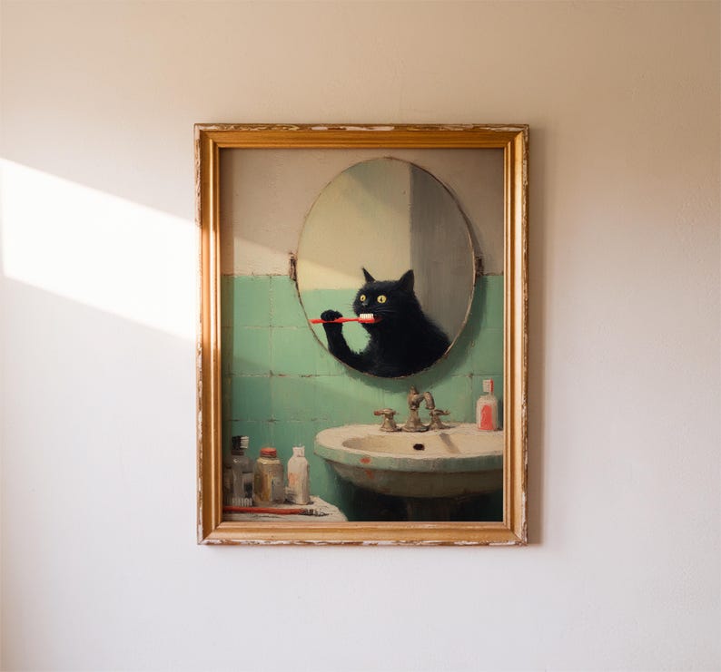 K&ouml;nnte beinhalten: Gerahmtes Kunstwerk, das eine schwarze Katze zeigt, die sich in einem Badezimmerspiegel die Z&auml;hne putzt. Die Katze spiegelt sich in einem runden Spiegel &uuml;ber einem Vintage-Waschbecken. Das Badezimmer hat eine gr&uuml;n geflieste Wand und einen goldfarbenen Rahmen.
