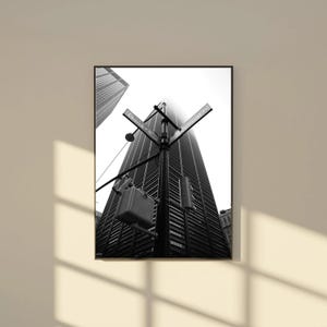 May include: Black and white photograph of a tall skyscraper with a street sign that reads "Church" and "Cortlandt". The image is framed and mounted on a wall. The sky is overcast.