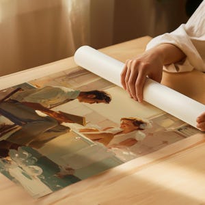 K&ouml;nnte beinhalten: Ein aufgerolltes wei&szlig;es Poster wird von H&auml;nden gehalten und zeigt ein Gem&auml;lde im Vintage-Stil. Das Kunstwerk zeigt einen Mann, der einer Frau in einem Badezimmer vorliest, mit warmen Farben und einem nostalgischen Gef&uuml;hl. Das Gem&auml;lde befindet sich auf einer Holzoberfl&auml;che.