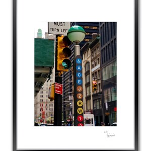A framed color photo shows a street light pole with a green traffic light and a vertical sign displaying subway line letters.