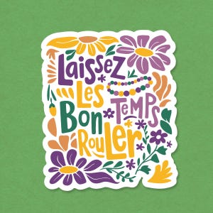 May include: A white sticker with the phrase "Laissez Les Bon Temps Rouler" in purple, green, and yellow, surrounded by floral and leaf illustrations. The background is a solid green color.