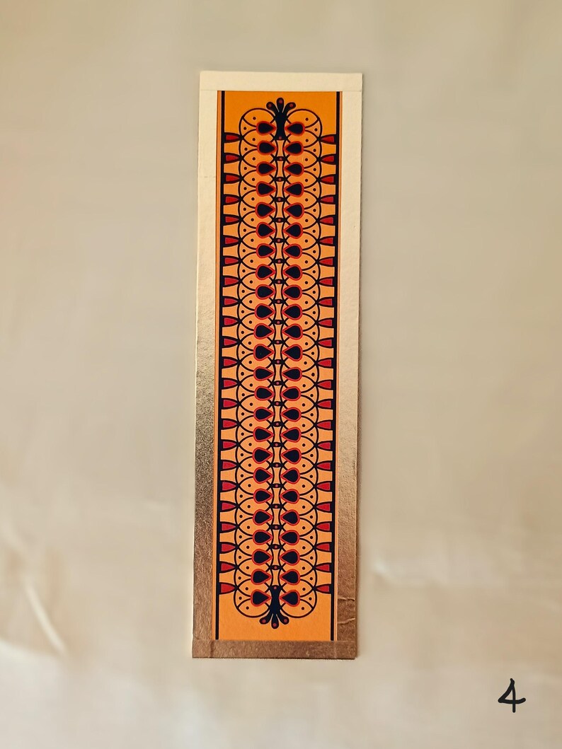 May include: A bookmark with a gold border and a repeating pattern of black, red, and orange shapes on a yellow background.