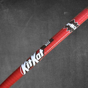 May include: A red Kit Kat candy bar with the text "Kit Kat" in white and a "King Size" label. The candy bar is wrapped in red packaging with a clear plastic end.