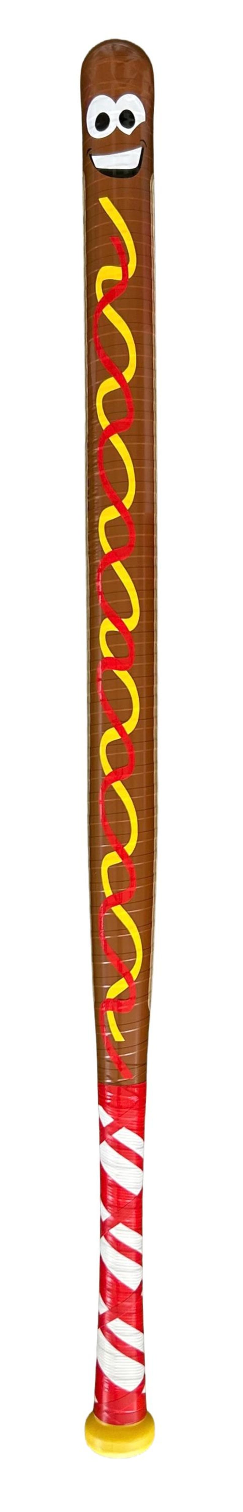 Op de afbeelding: Een novelty honkbalknuppel in de vorm van een hotdog. De bruine knuppel heeft een lachend gezicht, met gele en rode kronkellijnen om mosterd en ketchup voor te stellen. De handgreep is rood en wit gestreept.